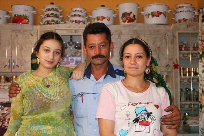 Perty, her father, and Klara Two sisters stand beside their father in their home kitchen.
