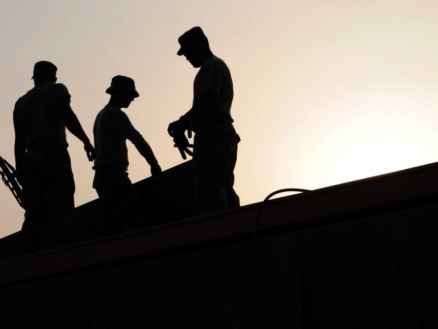 Silhouette of construction workers on roof
