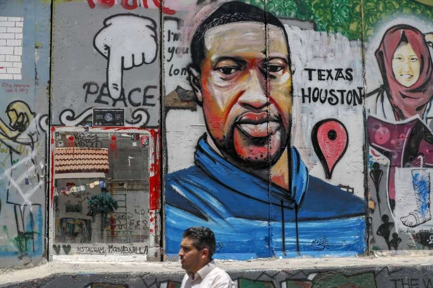 A Palestinian man walks past a graffiti of George Floyd painted on a section of Israel's controversial separation barrier in the city of Bethlehem in the occupied West Bank on June 8.