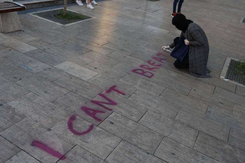 A hooded protester writes with graffiti spray 
