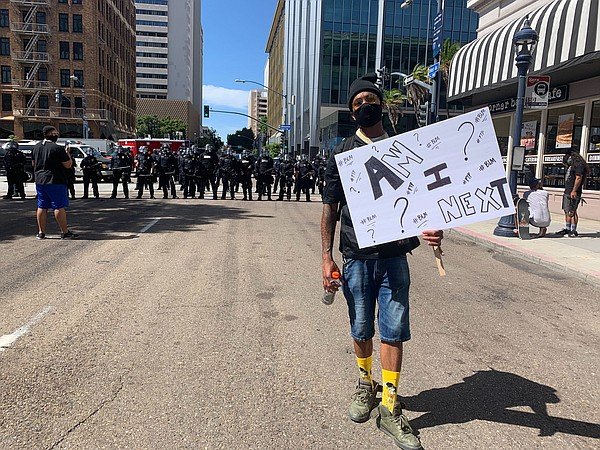 A protester walks with a sign during a protest over the d...