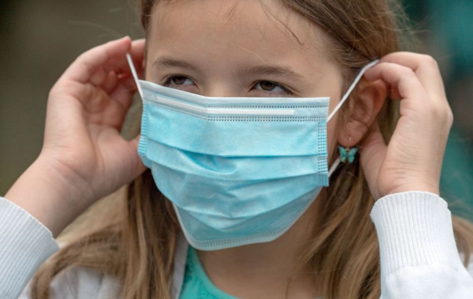 A primary school-aged girl puts on a mask before entering a school in Frankfurt. (Getty Images)