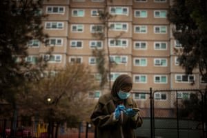 Hiba Shanino checks her mobile phone while wearing a face mask and gloves.