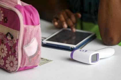 Beverly Okosun, right, program director, records the temperatures of students after they're dropped off Tuesday, July 14, 2020, at the Quillian Center in Houston.
