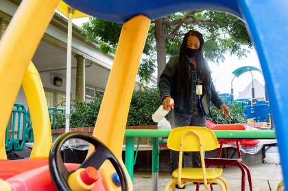 Caterpillar classroom teacher Dorene Hayes wears a mask while disinfecting playground equipment at Saint Vincent’s.