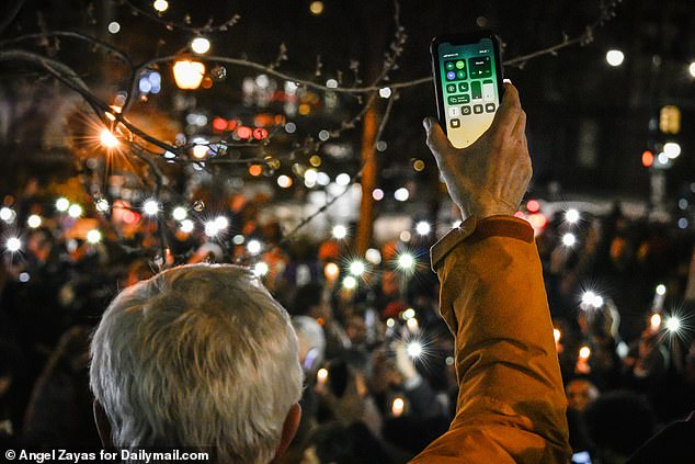 Mourners held up their cellphones as part of a vigil for the slain teenager on Sunday night