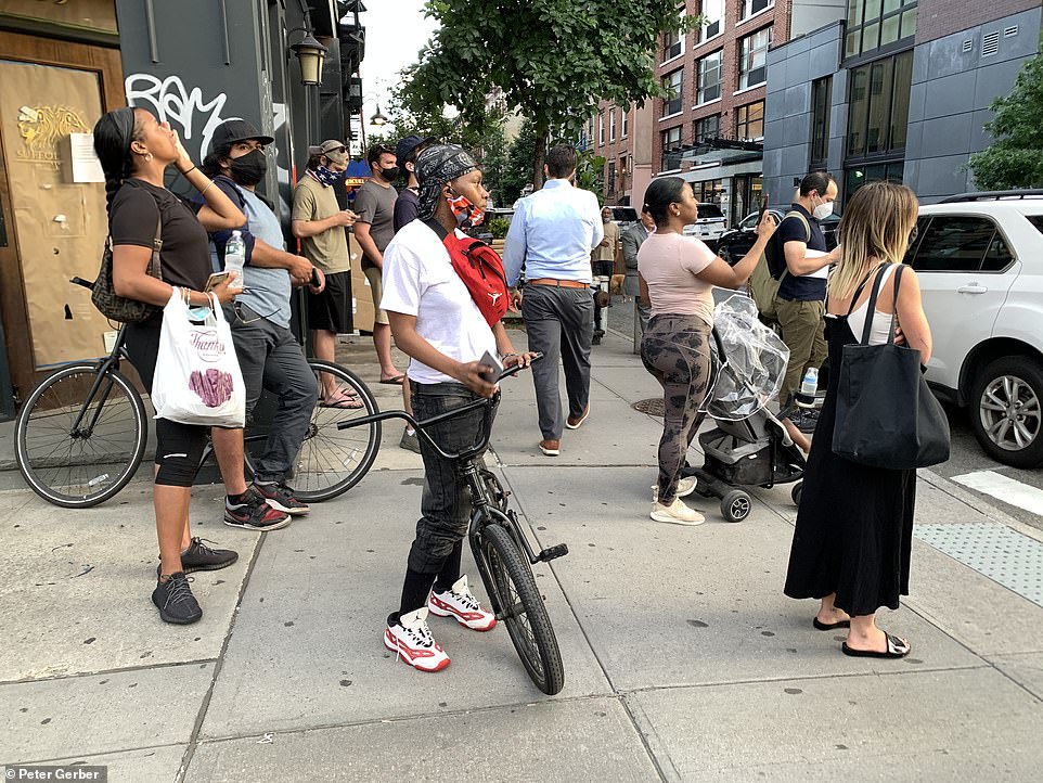 A crowd of people are seen gathered outside the apartment building in the Lower East Side neighborhood of Manhattan