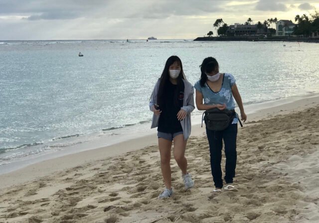 Beach goers at Ala Moana Beach Park wear masks as a COVID precaution in Honolulu, HI. (Ronen Zilberman photo Civil Beat)