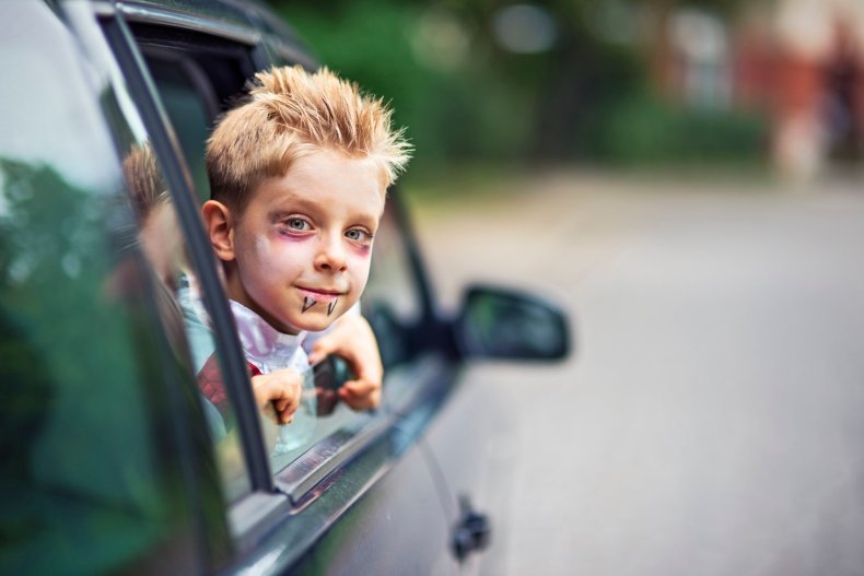 Little halloween boy smiling out of the car