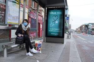 A woman wearing a protective face mask waits at a bus stop which displays a message of 'Thank you to Ireland's healthcare workers' in Dublin. Photo: REUTERS/Clodagh Kilcoyne