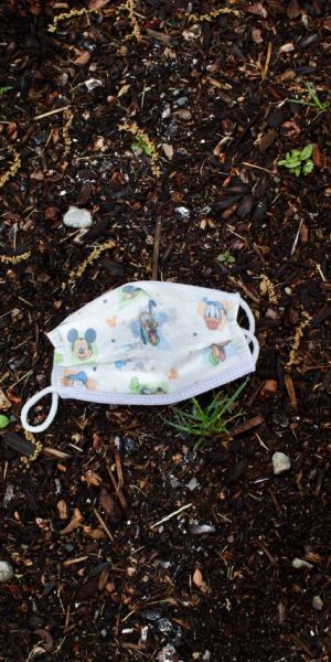 A Disney face mask lays in the dirt.