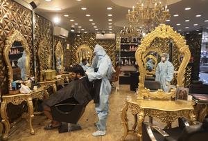 A hairdresser in a personal protective suit attends to a customer at a hair salon in New Delhi (Manish Swarup/AP)